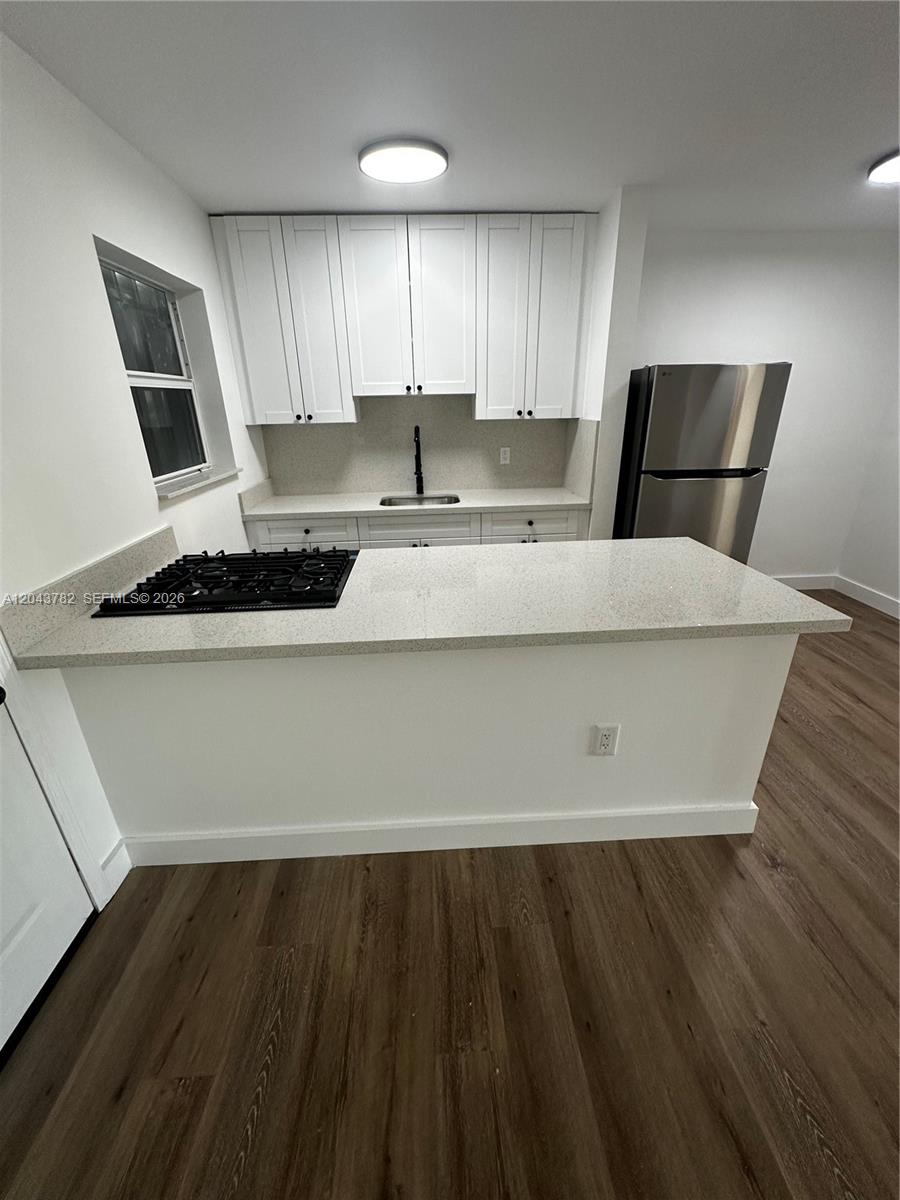 A kitchen features white cabinets, a quartz countertop, a gas cooktop, and stainless steel appliances — 1255 W 49th Pl # E205, Hialeah FL 33012, HIALEAH, FL