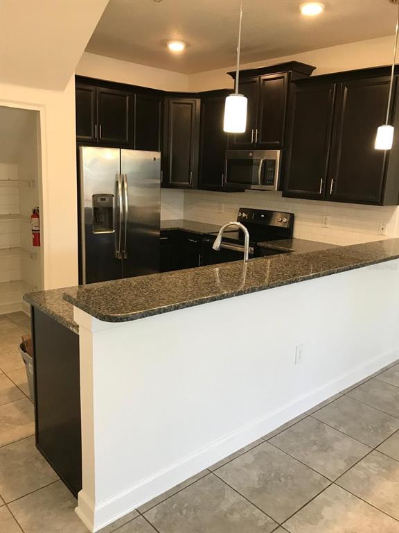 A kitchen features dark wood cabinets, granite countertops, stainless steel appliances, and a breakfast bar — 3348 RODRICK CIRCLE, ORLANDO, FL