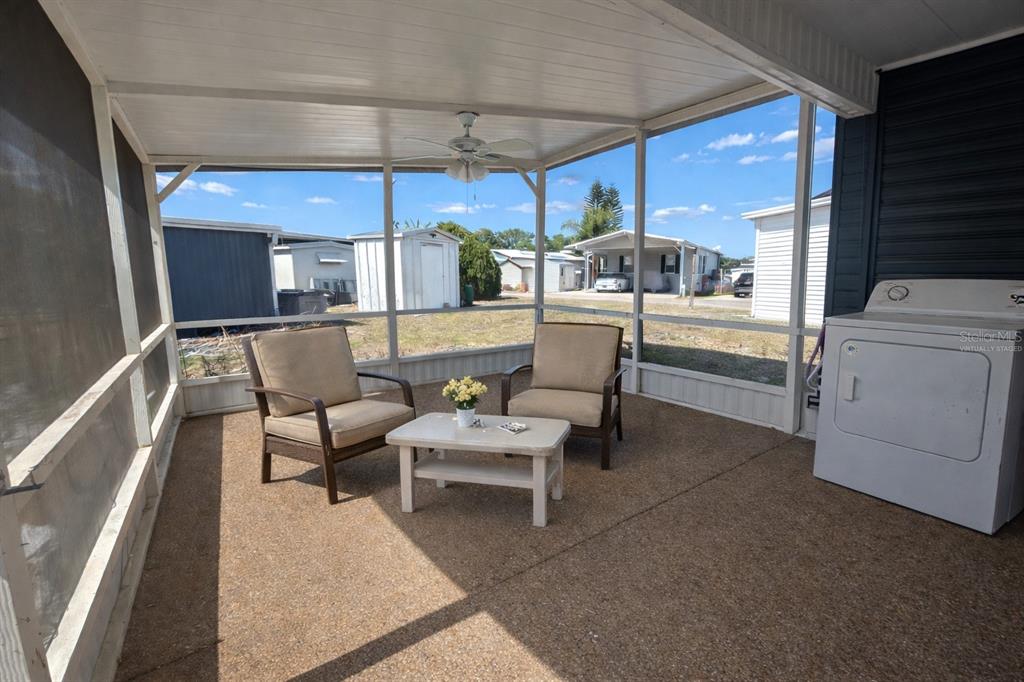 A screened-in porch features two armchairs, a small table, and a white clothes dryer — 6 RED QUILL CIRCLE, LAKE WALES, FL