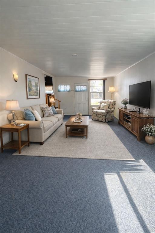 A living room features a beige sofa, floral armchair, wooden coffee table, and blue carpeting — 6 RED QUILL CIRCLE, LAKE WALES, FL