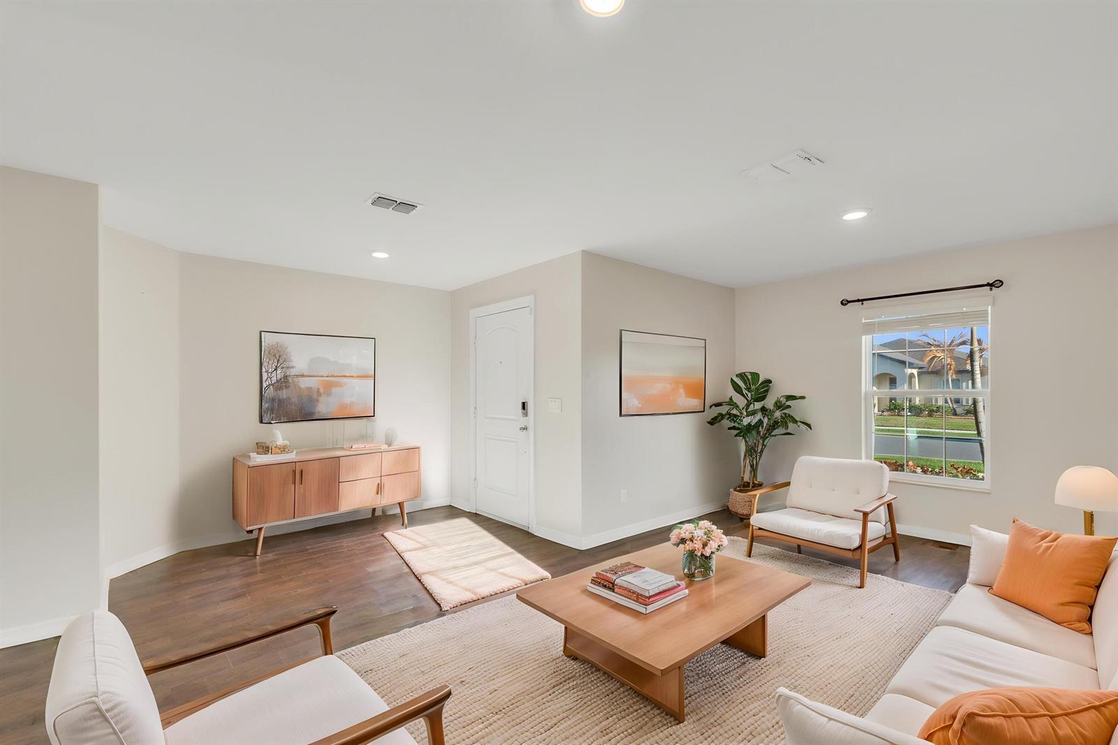 A living room features light-colored walls, wood flooring, a central coffee table, and seating furniture — 5532 Imagination Drive, Fort Pierce FL 34947, FORT PIERCE, FL