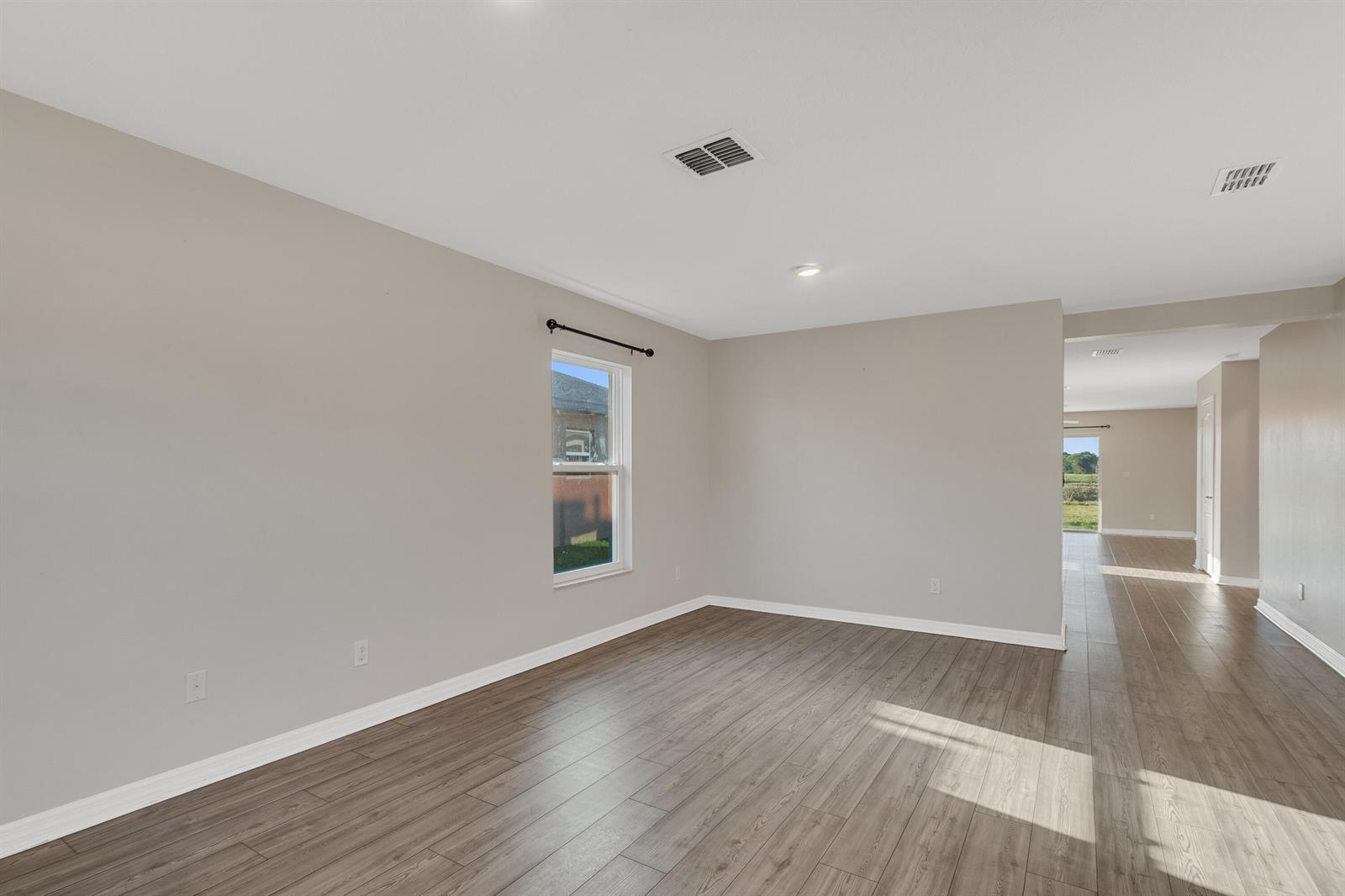 An empty room features light gray walls, wood-look flooring, and a single window — 5532 Imagination Drive, Fort Pierce FL 34947, FORT PIERCE, FL
