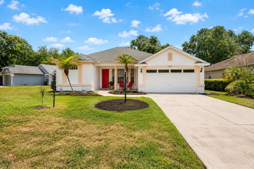 A single-story house with a white exterior, red front door, and a two-car garage — 3406 SILVERSTONE COURT, PLANT CITY, FL