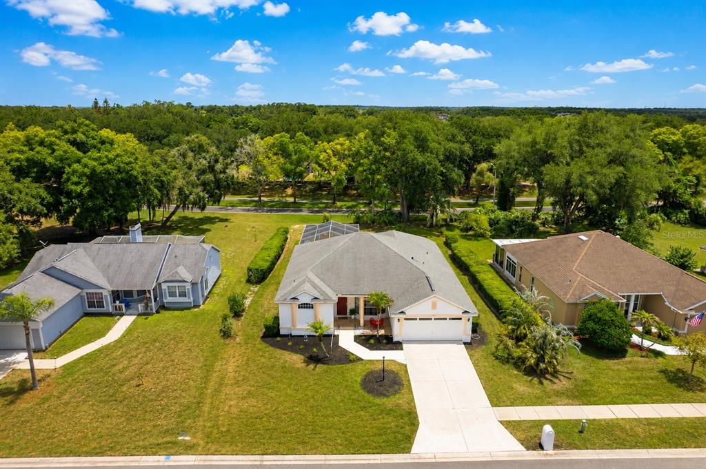An aerial view shows three suburban houses with lawns and trees under a blue sky — 3406 SILVERSTONE COURT, PLANT CITY, FL