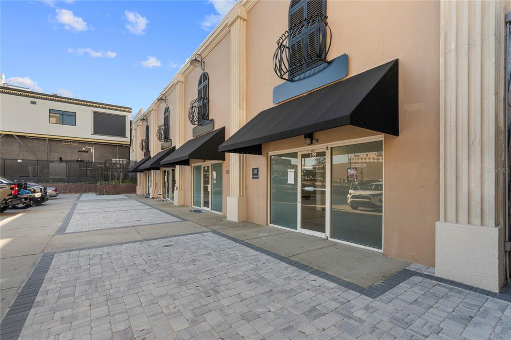 A row of commercial storefronts with black awnings and decorative iron balconies under a blue sky — 120 SW BROADWAY STREET, OCALA, FL