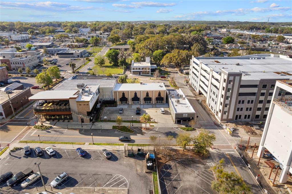 An aerial view shows a commercial building with a parking lot and surrounding urban infrastructure — 120 SW BROADWAY STREET, OCALA, FL