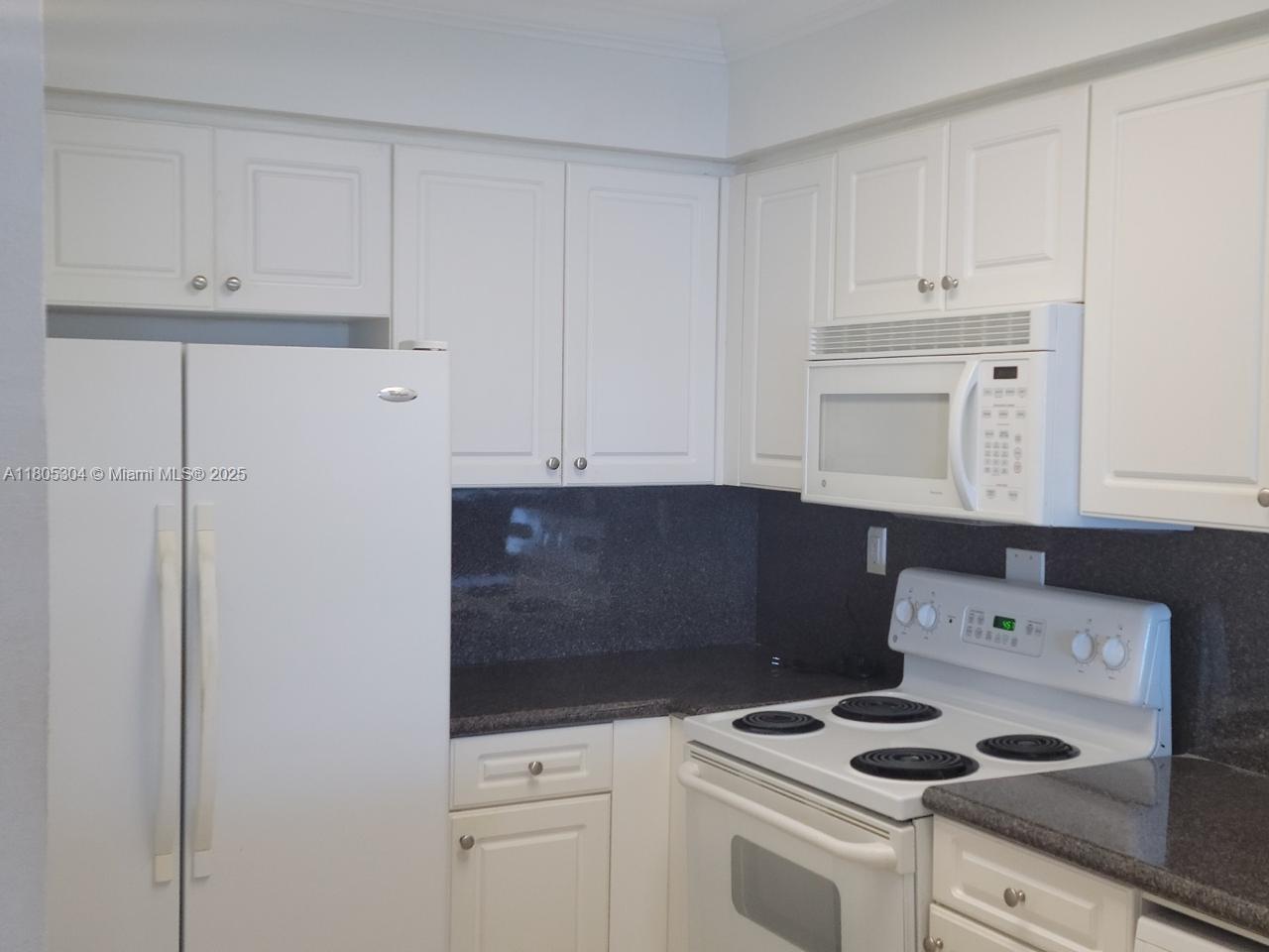 A kitchen features white cabinets, a white refrigerator, a white stove, and dark countertops — 2501 S Ocean Dr # 1634, Hollywood FL 33019, HOLLYWOOD, FL