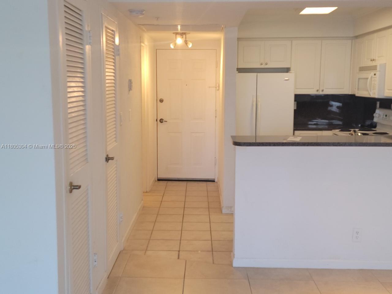 A tiled entryway leads to a white front door next to a kitchen with white cabinets — 2501 S Ocean Dr # 1634, Hollywood FL 33019, HOLLYWOOD, FL