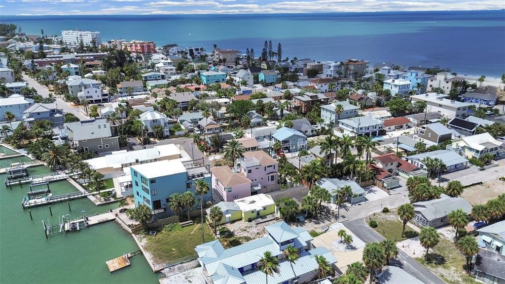 An aerial view shows a coastal neighborhood with houses, palm trees, and boat docks — 130 90TH AVENUE, TREASURE ISLAND, FL