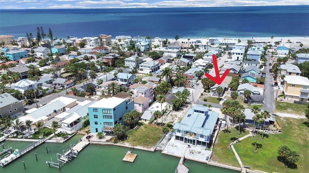 An aerial view shows a coastal neighborhood with houses, palm trees, and a canal — 130 90TH AVENUE, TREASURE ISLAND, FL
