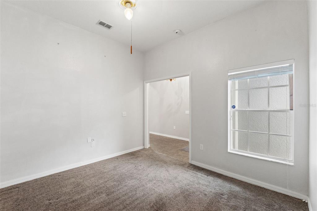 An empty room with gray carpet, white walls, a ceiling fan, and a window — 4490 AYRSHIRE DRIVE, SPRING HILL, FL