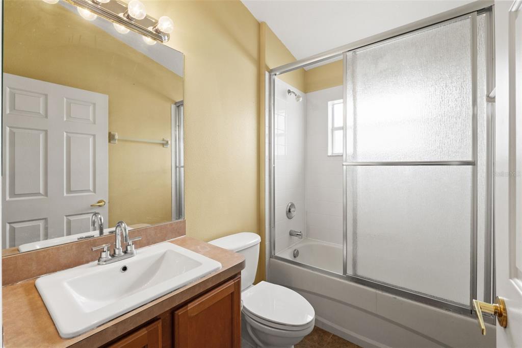 A bathroom features a vanity with a white sink, a toilet, and a shower-tub combo — 4490 AYRSHIRE DRIVE, SPRING HILL, FL
