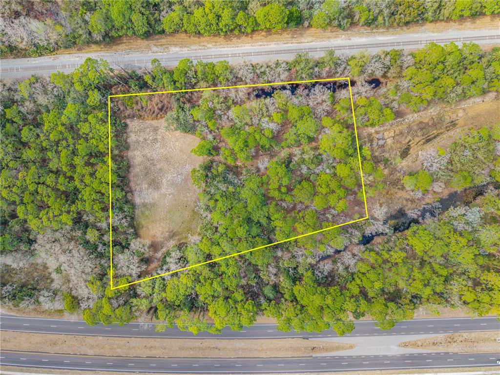 An aerial view shows a rectangular plot of land outlined in yellow near a highway — 370 S US HIGHWAY 1, OAK HILL, FL