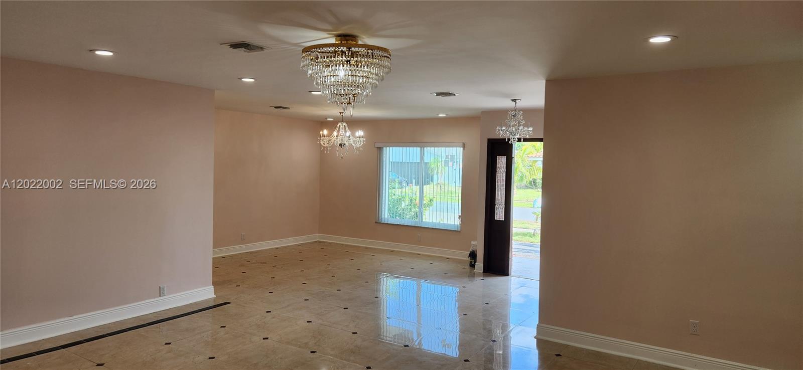 An empty room features beige tile floors, recessed lighting, and two crystal chandeliers — 5260 SW 9th St, Plantation FL 33317, PLANTATION, FL