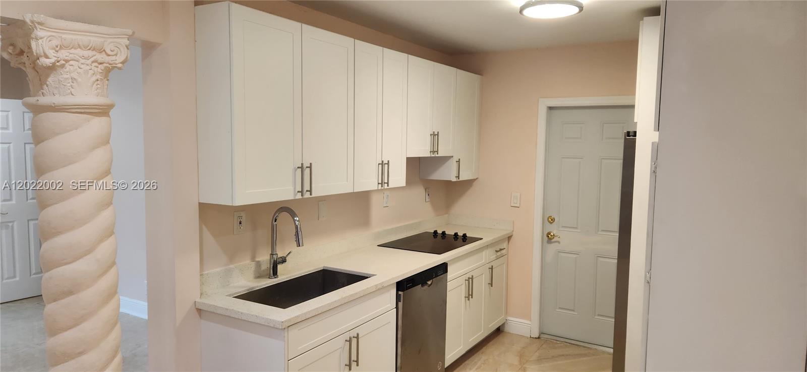 A kitchen features white cabinets, light countertops, a sink, a cooktop, and a decorative column — 5260 SW 9th St, Plantation FL 33317, PLANTATION, FL