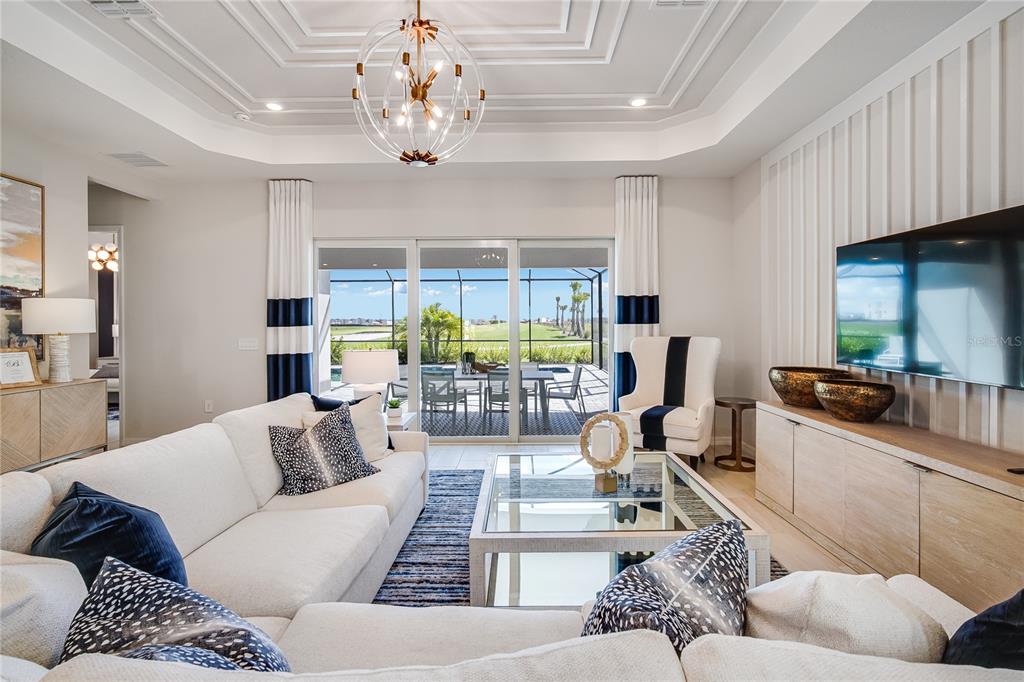 A living room features a white sectional sofa, glass coffee table, and sliding glass doors — 7165 INLET ISLES COURT, LAKEWOOD RANCH, FL