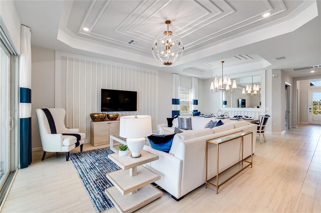 A bright living room features a white sectional sofa, a globe chandelier, and board-and-batten walls — 7165 INLET ISLES COURT, LAKEWOOD RANCH, FL