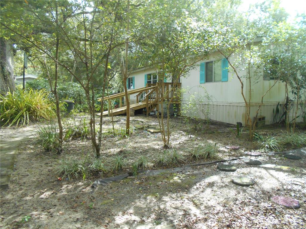 A large, moss-covered oak tree stands in the yard next to a mobile home — 20425 NE 143RD STREET, SALT SPRINGS, FL
