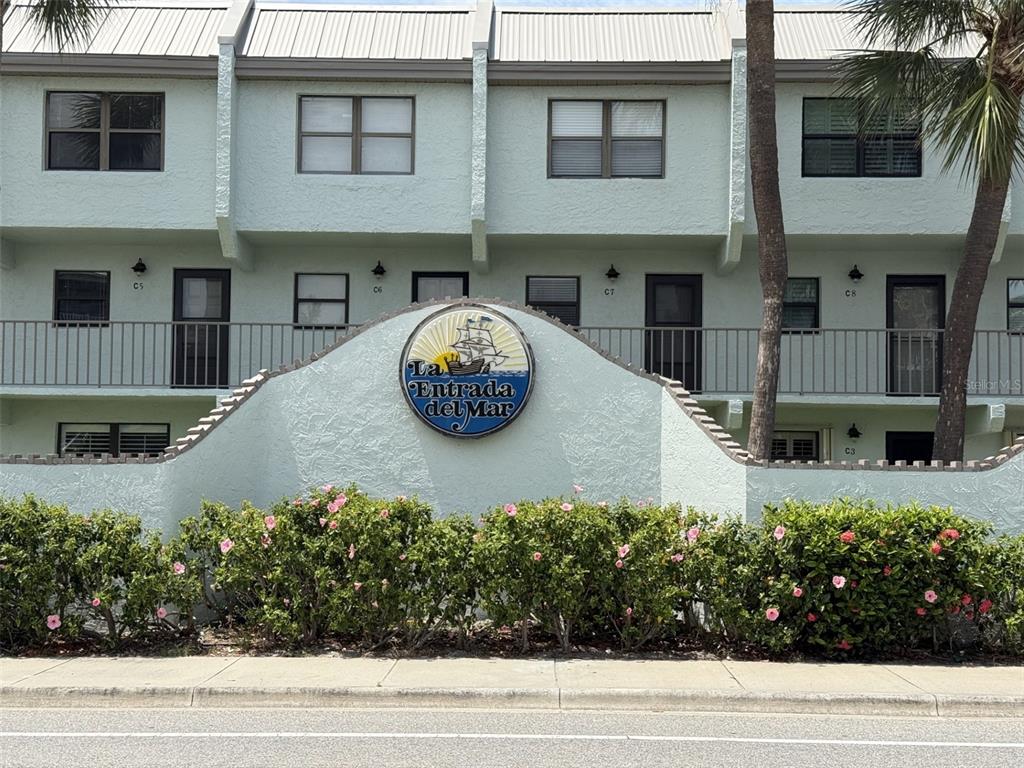 A light green multi-story apartment building features a prominent circular sign for La Entrada del Mar — 1300 SEAWAY DRIVE UNIT C1, HUTCHINSON ISLAND, FL