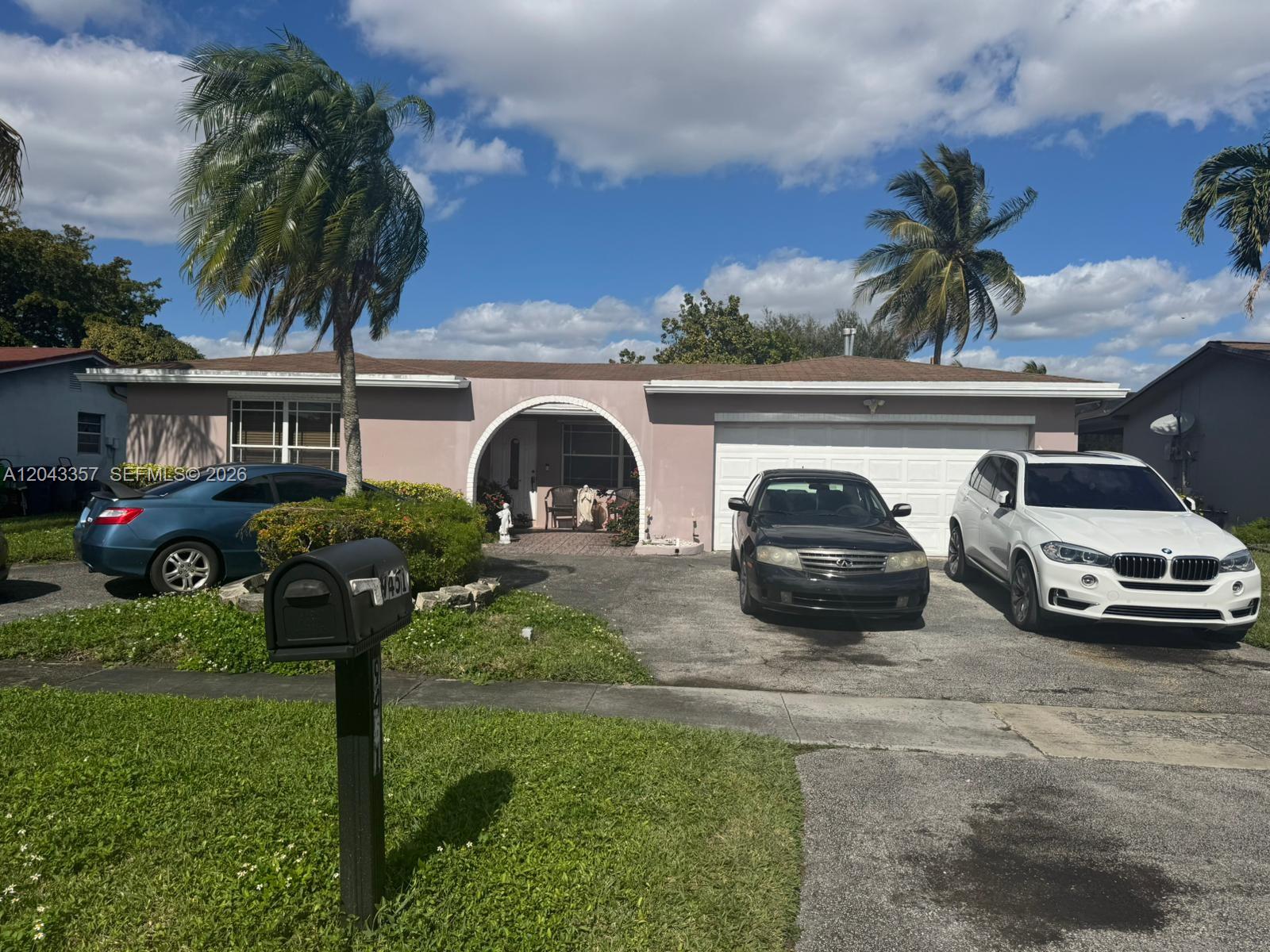A single-story house with a pink exterior, arched entryway, and a two-car driveway — 9451 NW 20th Pl, Sunrise FL 33322, SUNRISE, FL
