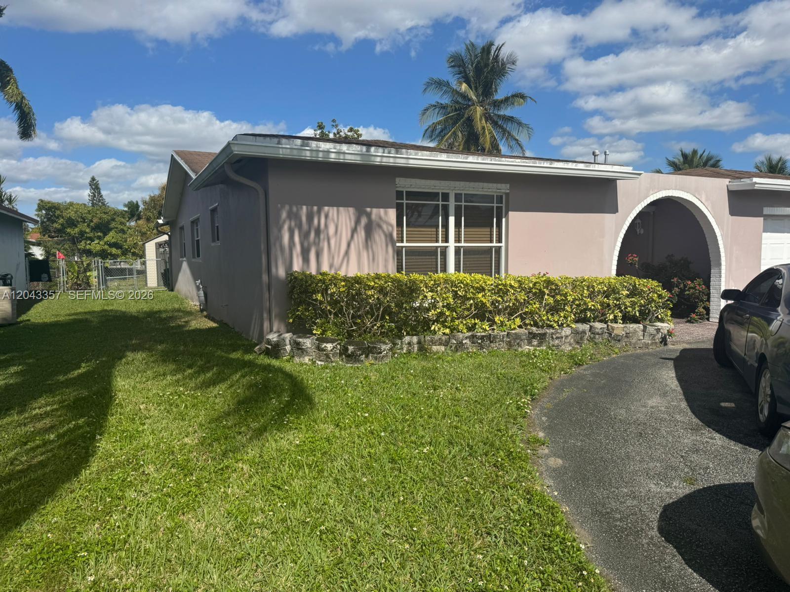 A single-story house with a beige exterior, arched entryway, and a landscaped front yard — 9451 NW 20th Pl, Sunrise FL 33322, SUNRISE, FL