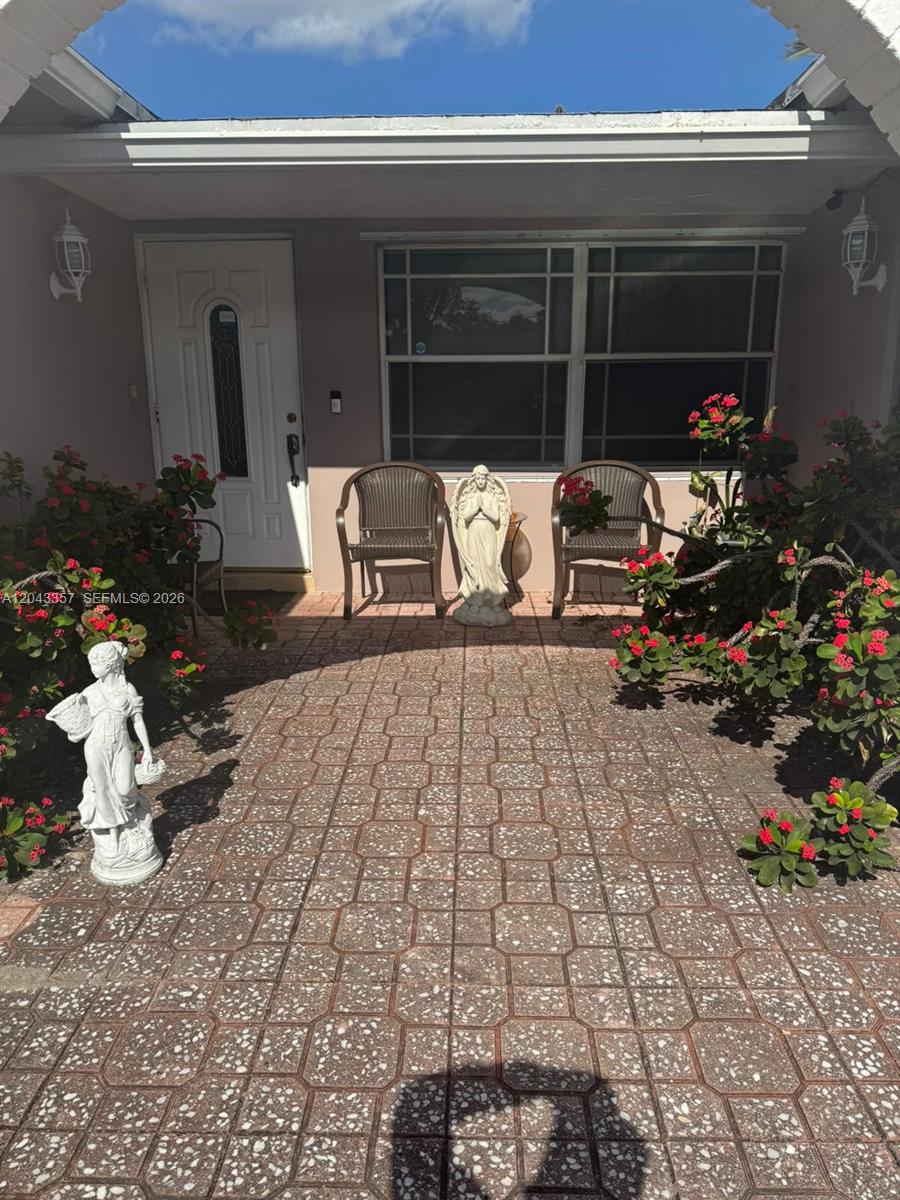 A paved front patio features two chairs, two statues, and potted flowering plants — 9451 NW 20th Pl, Sunrise FL 33322, SUNRISE, FL