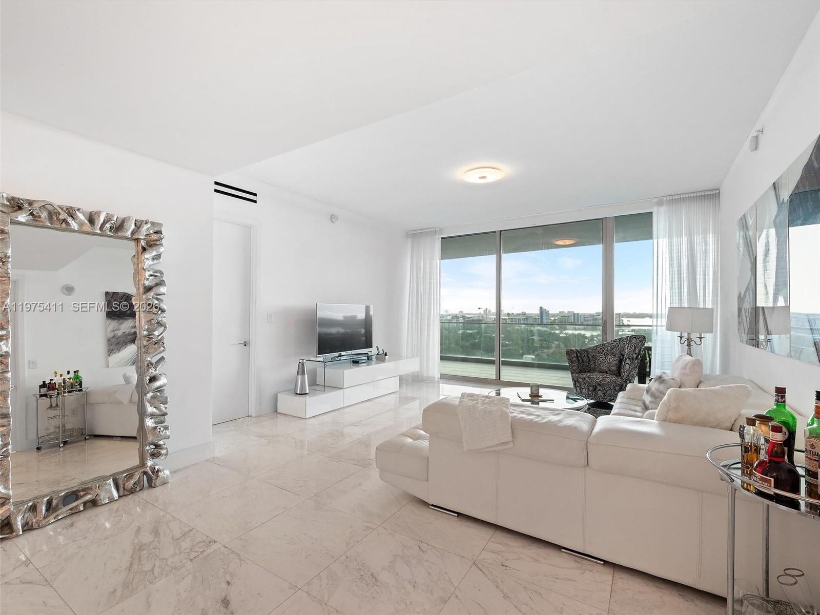 A bright living room features white leather furniture, marble floors, and a large balcony view — 10203 Collins Ave # 1105, Bal Harbour FL 33154, BAL HARBOUR, FL