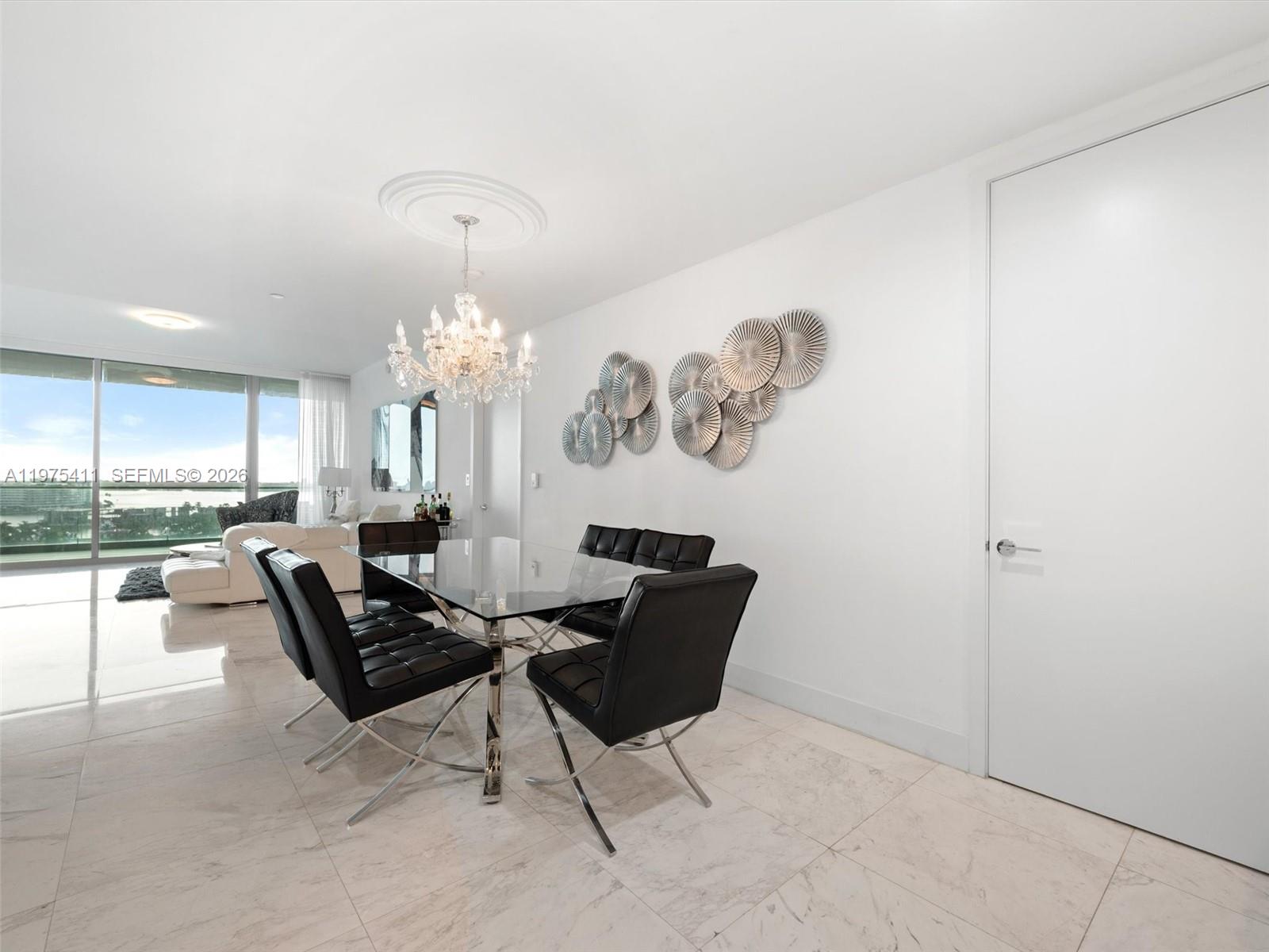 A dining room features a glass table, black chairs, a crystal chandelier, and marble flooring — 10203 Collins Ave # 1105, Bal Harbour FL 33154, BAL HARBOUR, FL