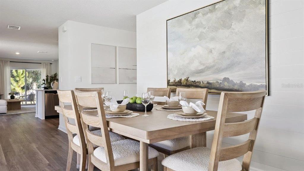 A dining room features a wooden table with chairs, shiplap walls, and a large landscape painting — 4423 LAKE FOX DRIVE, LAKELAND, FL