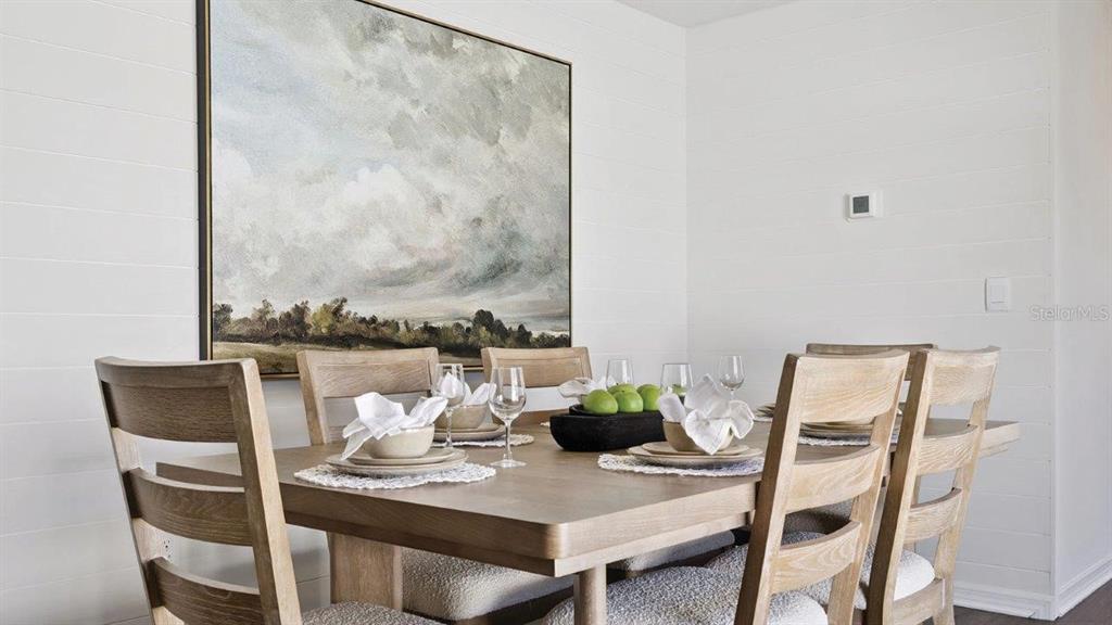 A dining room features a wooden table with chairs, place settings, and a large landscape painting — 4423 LAKE FOX DRIVE, LAKELAND, FL