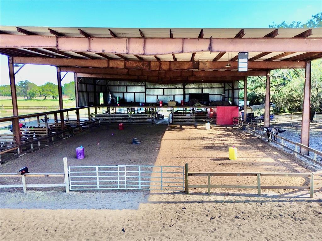 An open-air horse riding arena features a metal roof, dirt floor, and perimeter fencing — 3046 N BOWDEN ROAD, AVON PARK, FL