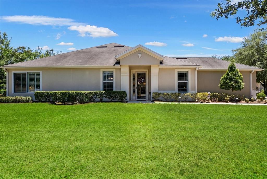A single-story house with a beige exterior, a gabled entryway, and a large front lawn — 6631 SW 91ST CIRCLE, OCALA, FL
