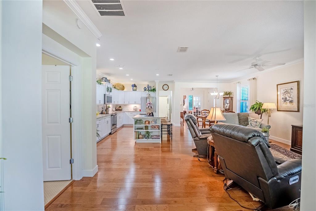 An open-concept kitchen and living area features hardwood floors, white cabinetry, and leather recliners — 6631 SW 91ST CIRCLE, OCALA, FL