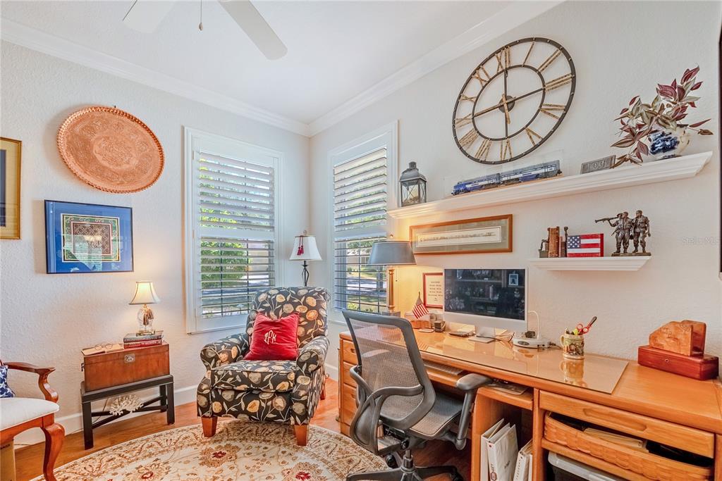 A home office features a wooden desk, an armchair, two windows, and wall-mounted shelves — 6631 SW 91ST CIRCLE, OCALA, FL
