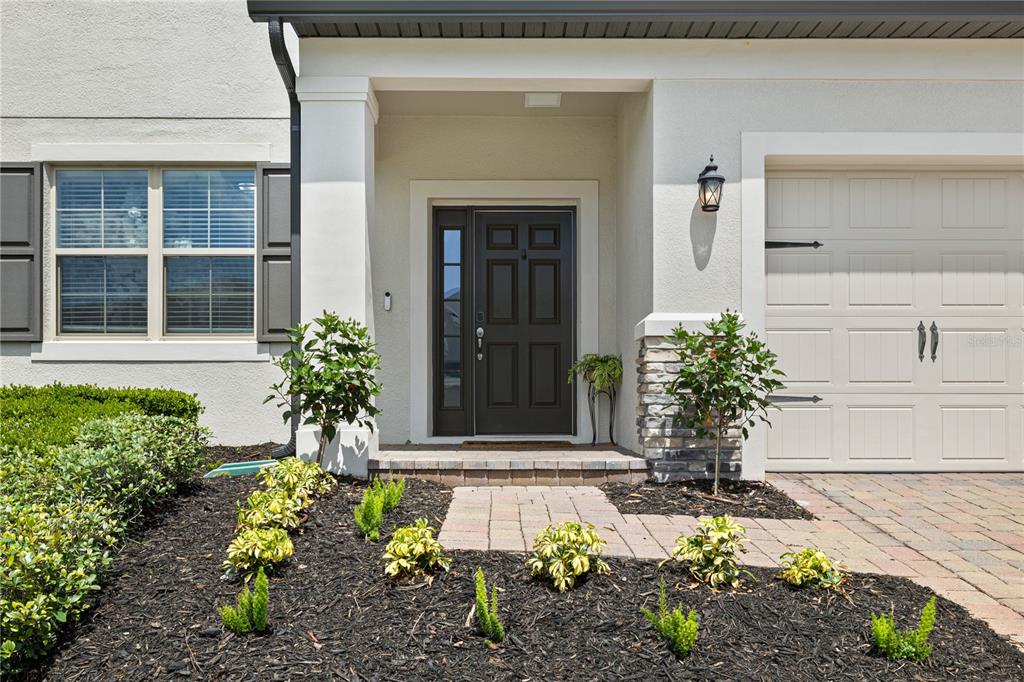 The exterior of a house features a dark front door, stone accents, and a garage — 13320 MAGNOLIA VALLEY DRIVE, CLERMONT, FL