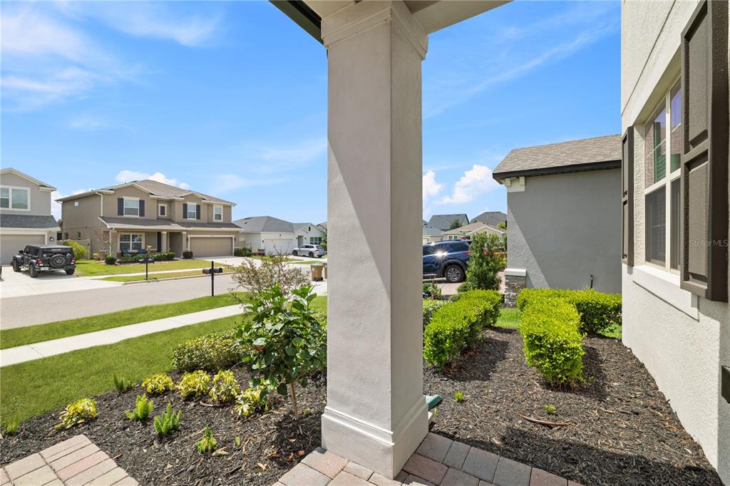 A view from a covered porch looking out toward a suburban street and neighboring houses — 13320 MAGNOLIA VALLEY DRIVE, CLERMONT, FL