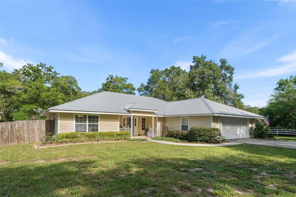 A single-story house with light yellow siding, a metal roof, and a two-car garage — 646 NE 2ND STREET, WILLISTON, FL
