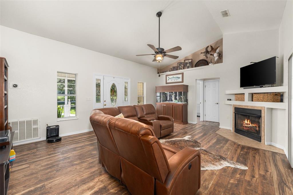 A living room features a leather sectional, fireplace, television, and wood-look flooring — 646 NE 2ND STREET, WILLISTON, FL