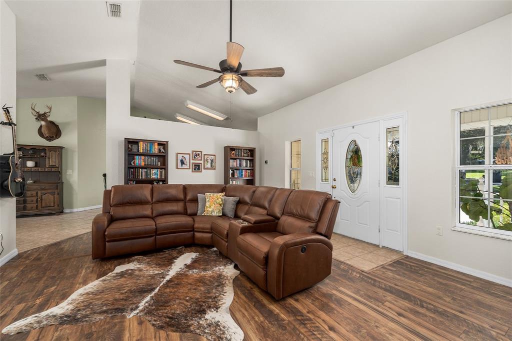 A living room features a brown leather sectional, a cowhide rug, and a ceiling fan — 646 NE 2ND STREET, WILLISTON, FL