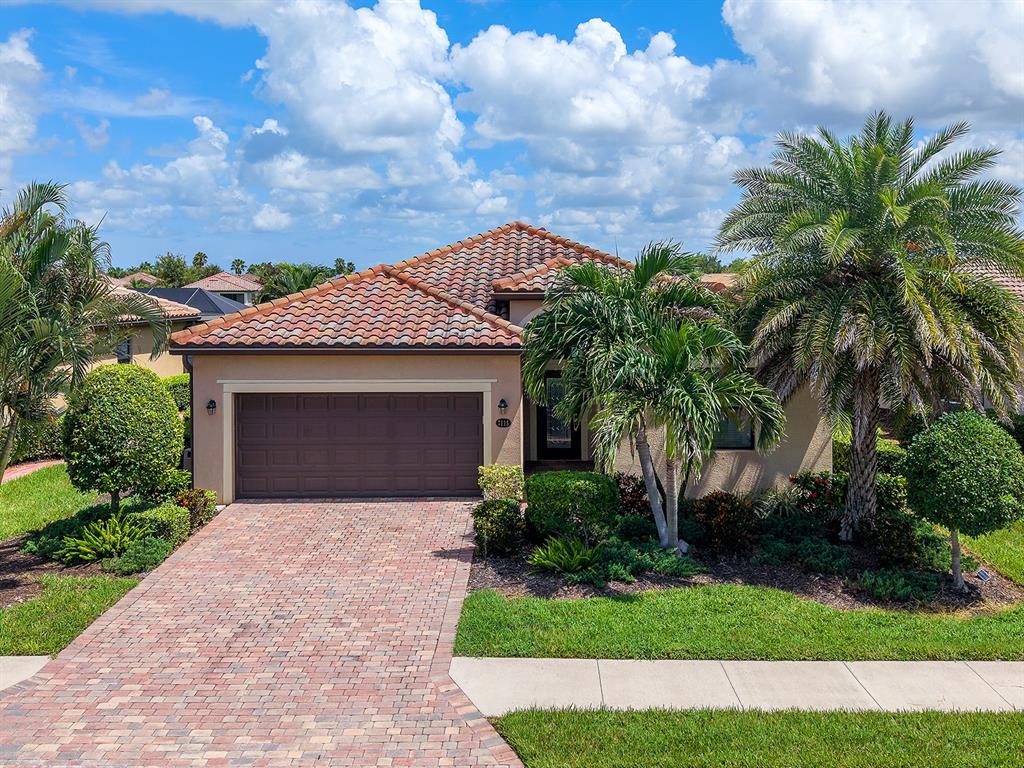 An aerial view shows a single-story house with a tiled roof situated by a lake — 7115 MARSH VIEW TERRACE, BRADENTON, FL