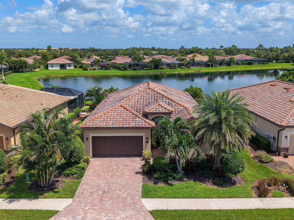 An aerial view shows a residential house with a screened pool enclosure facing a lake — 7115 MARSH VIEW TERRACE, BRADENTON, FL
