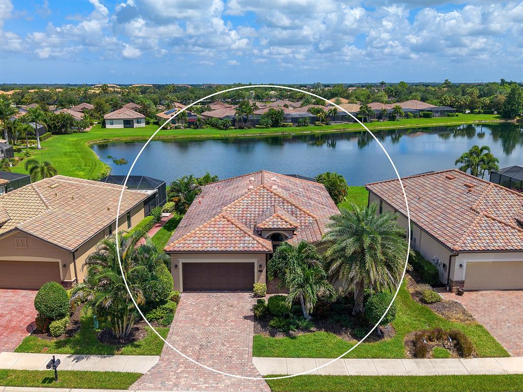 A single-story house with a tiled roof, brown garage door, and palm trees in front — 7115 MARSH VIEW TERRACE, BRADENTON, FL