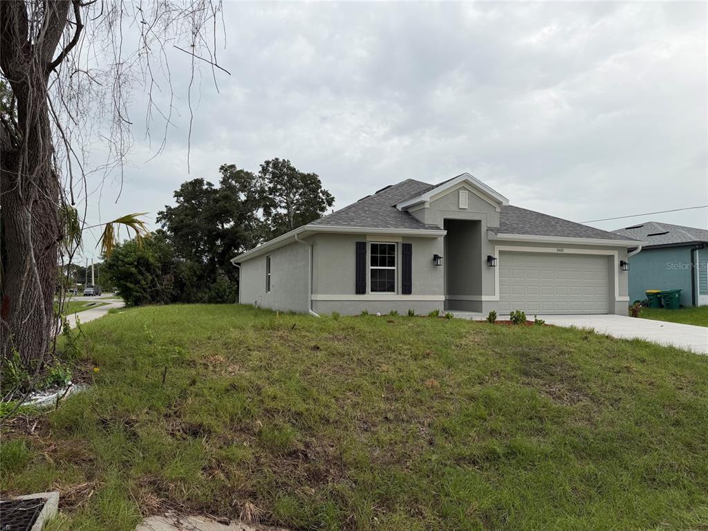 A single-story house with a gray stucco exterior, a two-car garage, and a grassy yard — 21426 DEKALS AVENUE, PORT CHARLOTTE, FL