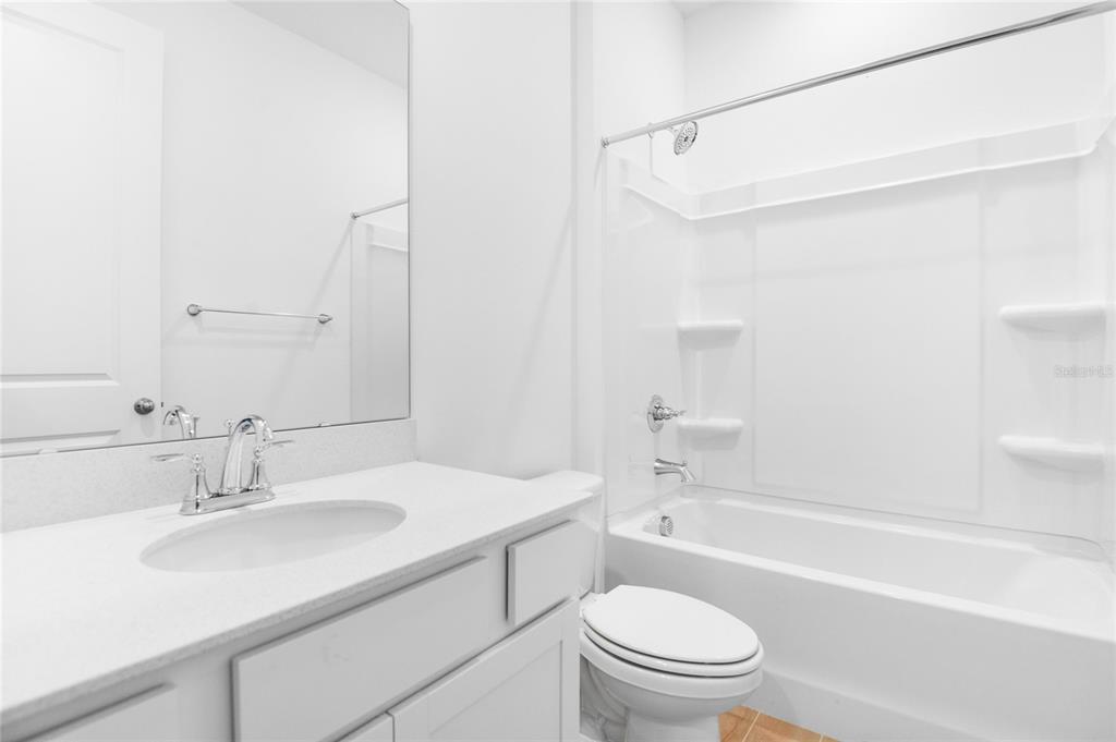 A bathroom features a white vanity with a sink, a toilet, and a tub-shower combo — 6166 DAPHNE STREET, LAKE HAMILTON, FL