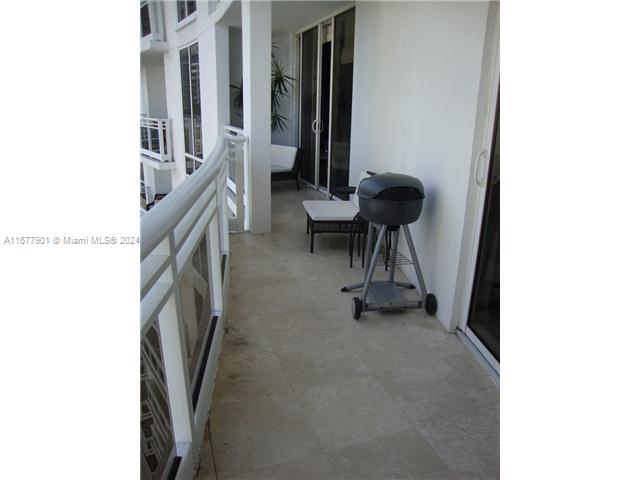 A balcony features light-colored stone flooring, a white railing, a grill, and patio furniture — 901 Brickell Key Blvd # 1701, Miami FL 33131, MIAMI, FL