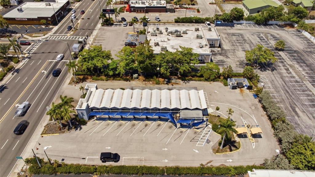 An aerial view shows a commercial building with a sawtooth roof and a parking lot — 3821 CLEVELAND AVENUE, FORT MYERS, FL