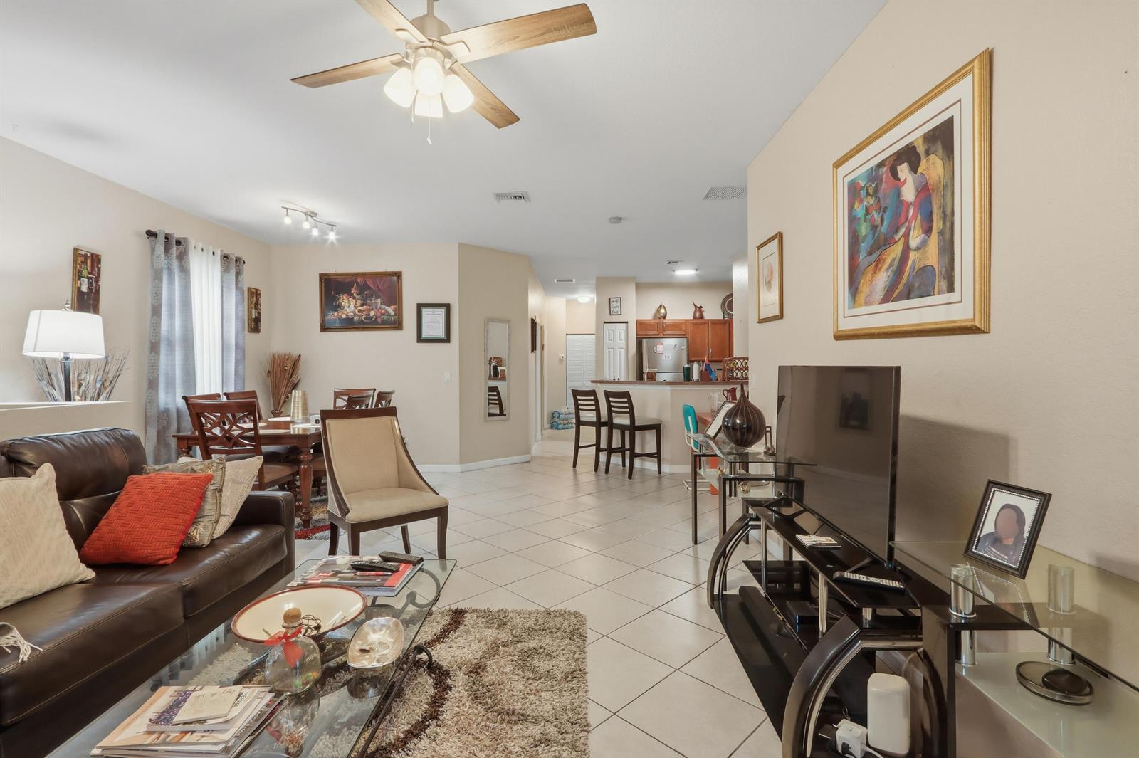 A living room with tile floors, a brown leather sofa, and an open kitchen area — 3108 Grandiflora Drive, FL 33467, FL