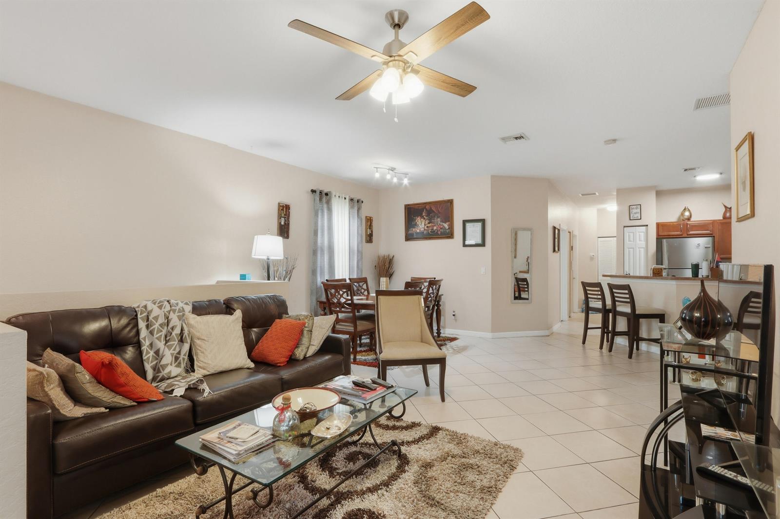 An open-concept living and dining area features tile flooring, a leather sofa, and ceiling fan — 3108 Grandiflora Drive, FL 33467, FL