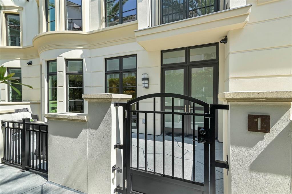 A black metal gate leads to the entrance of a cream-colored building with dark windows — 125 S INTERLACHEN AVENUE UNIT 1, WINTER PARK, FL