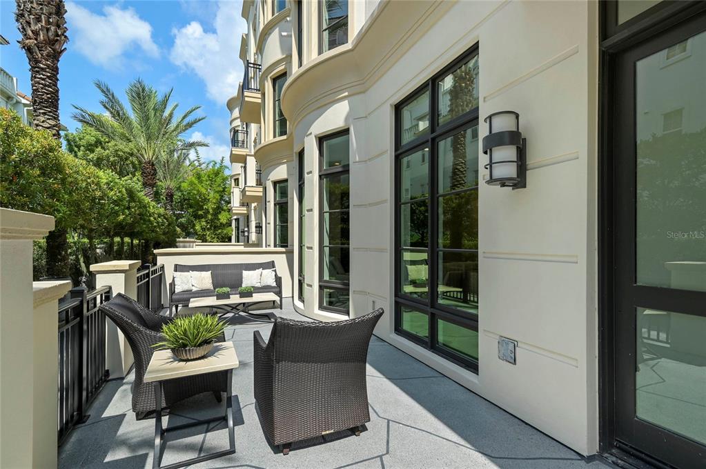 A patio with dark wicker furniture, a small table, and large windows on a building exterior — 125 S INTERLACHEN AVENUE UNIT 1, WINTER PARK, FL